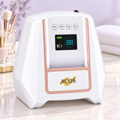 A white and rose gold ACOS beauty device with a digital display screen, set on a marble countertop with a blurred background of cosmetics and towels.
